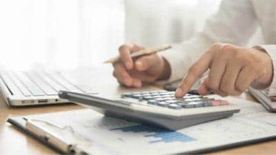 edit Businessman using calculator next to laptop