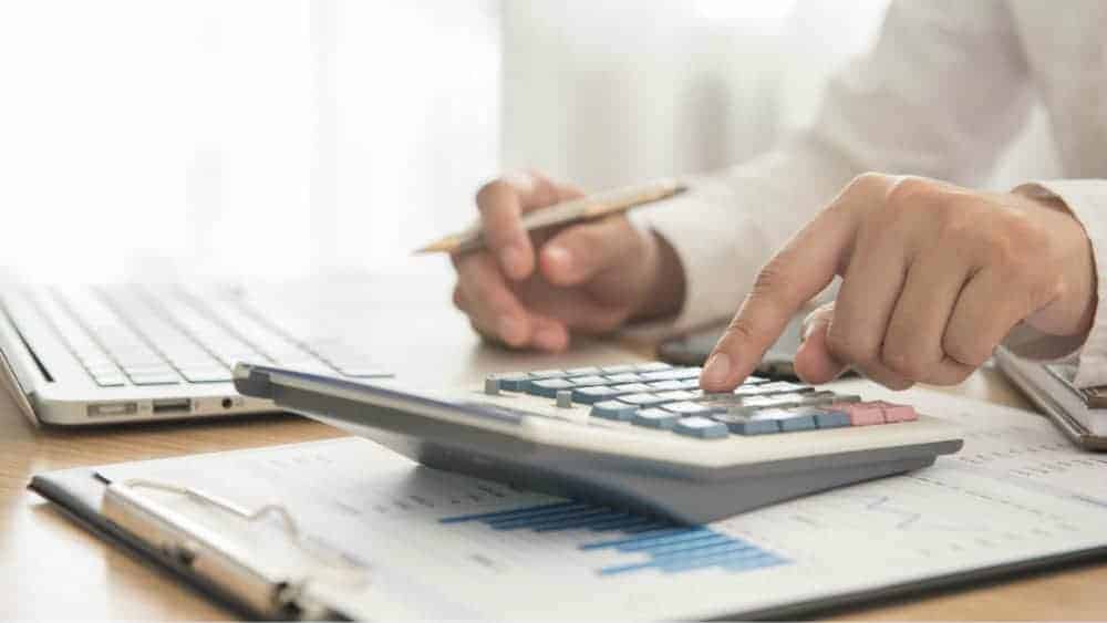 edit Businessman using calculator next to laptop