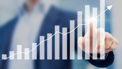 Business success with growing, rising charts and businessman in background