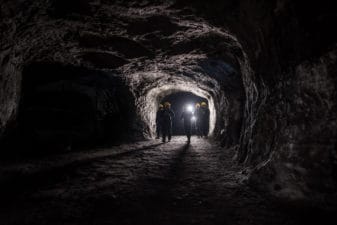People walk into a dark underground mine.