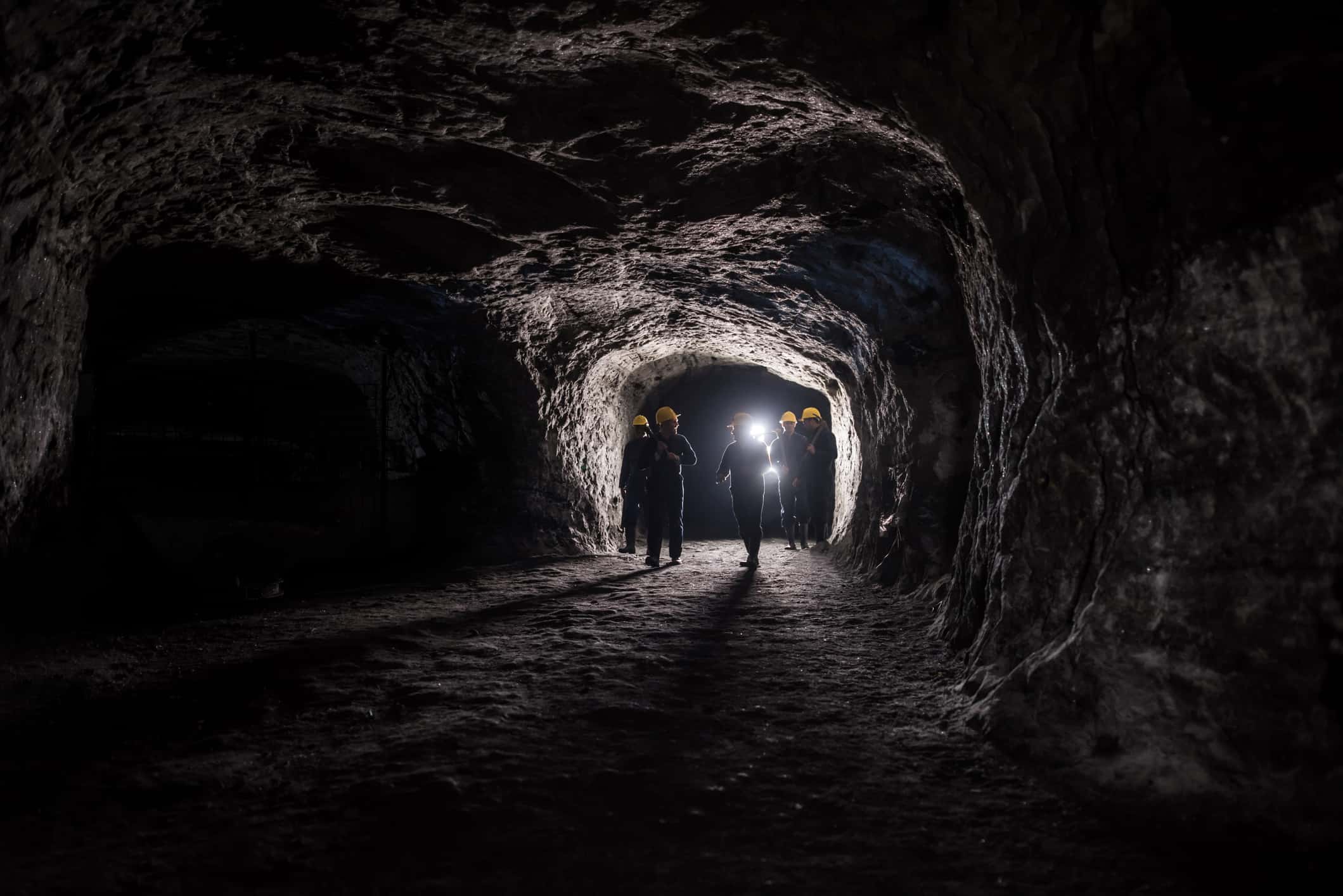 People walk into a dark underground mine.